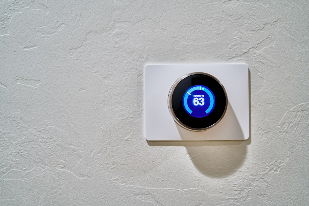 A white thermostat on a wall with heat set to 63